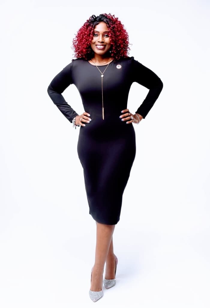 Portrait of Dr. Casita M. Adams, standing and smiling in a black dress against a white backdrop